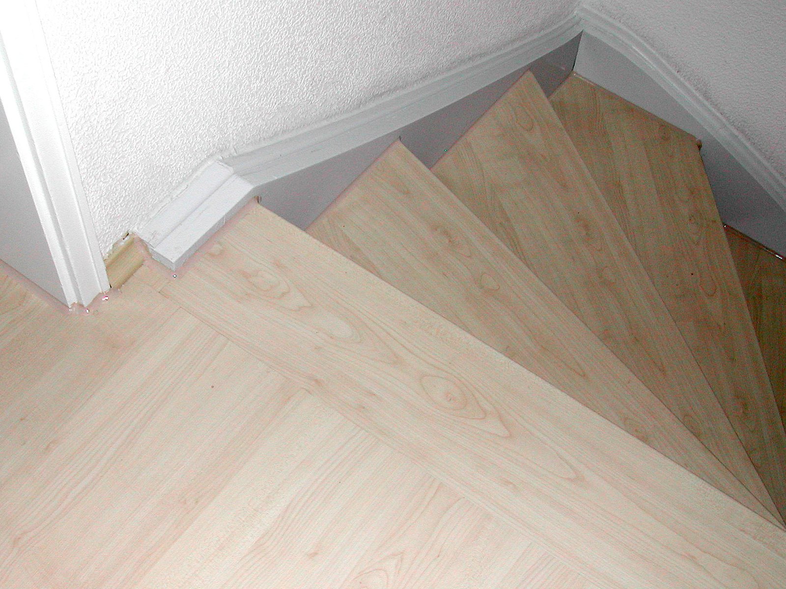 Gewendelte Treppe mit hellen, neu belegten Holzstufen